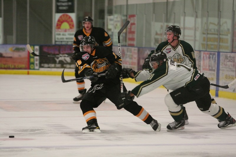 Olds Grizzly Taylor Bourne keeps an eye on the puck while Okotoks Oiler Matt Strong tries to push him off stride.