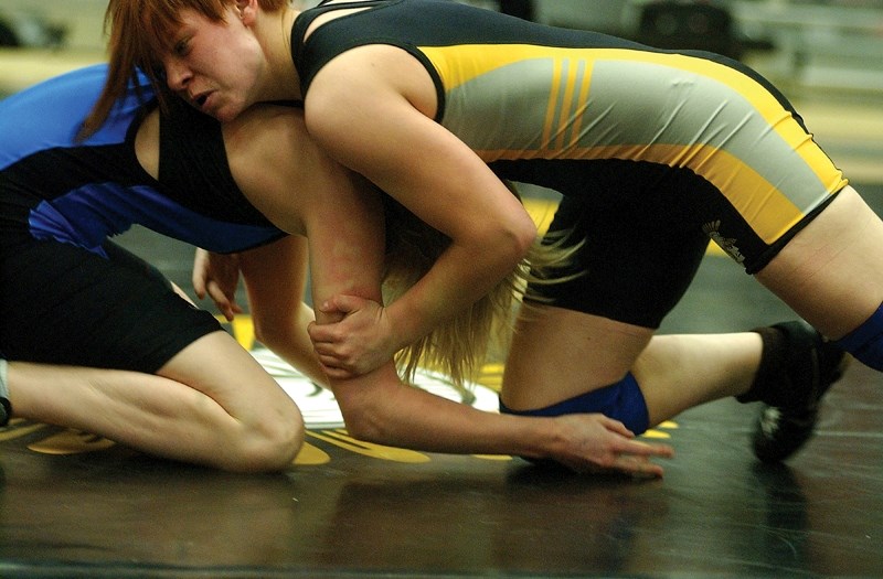 Olds High School wrestler Amber Maschke, 16, shows a determined look as she gets the upper hand on Fort McMurray&#8217;s Kelsey Munn during her opening bout of the rural