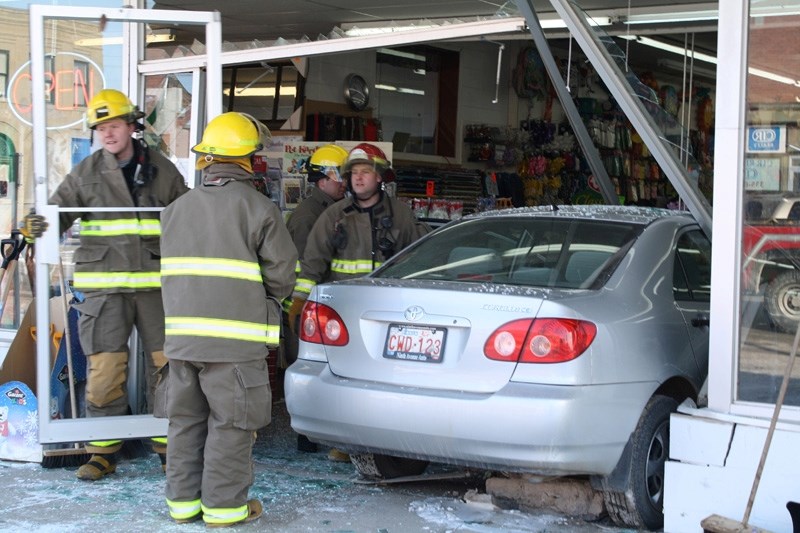 Didsbury fire fighters clean up debris and remove a car from the inside of Dollar Store &amp; More. An 81-year old woman from Olds drove through the storefront Friday morning.