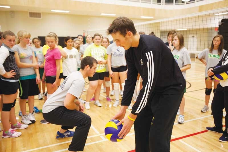Olds College volleyball players Lance Davidson, middle left, and Kennan Hedley show a diving technique to a group of grade 7 and 8 students from around the county at the