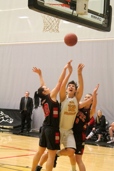 Olds College&#8217;s Melanie Hogue scrambles for a rebound against Grande Prairie Wolves Amy Kobzey (left) and Kelly O&#8217;Hallahan on Feb. 22 at the Ralph Klein Centre.