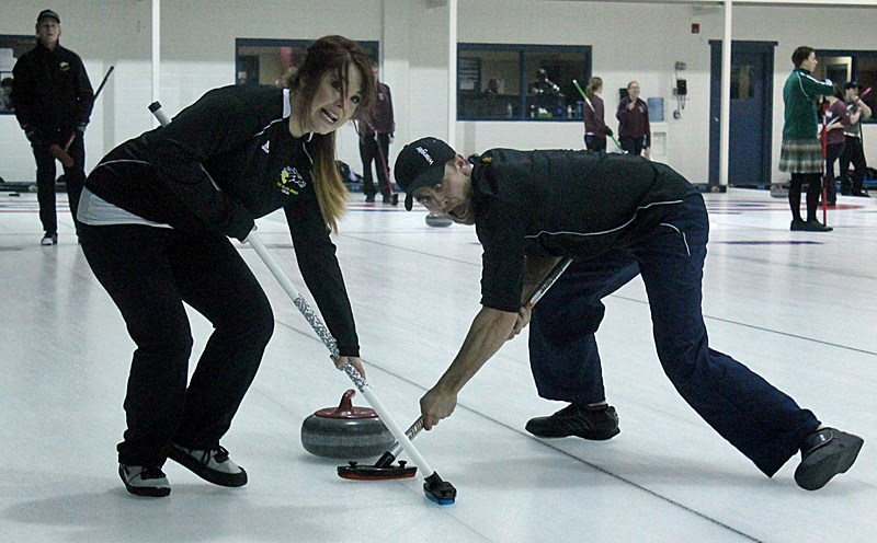 Olds College&#8217;s mixed curling team lead Becky Strause and second Ryan Cameron give their all during their opening game in the Alberta Colleges Athletic Conference