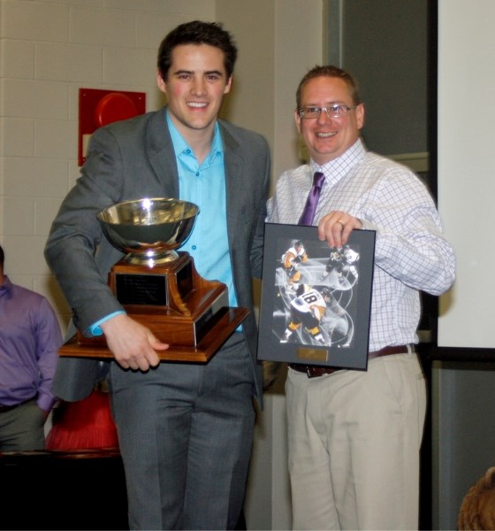 Brandon Clowes is presented with the regular season most valuable player award by Stephen Schooler, a member of the Olds Grizzlys board of directors, on April 27 at the