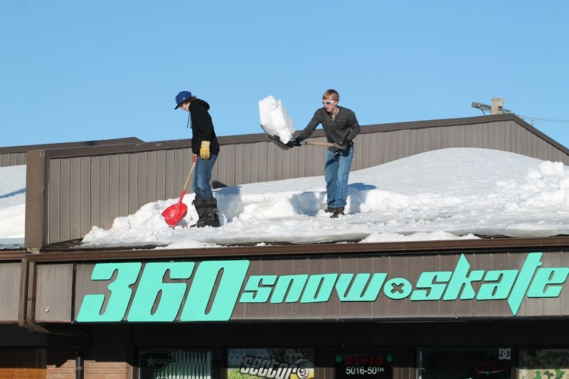 Workers clear snow from the roof of 360 Snow and Skate on 50 Street on the afternoon of Jan. 25. Heavy snowfall in recent weeks has caused roof collapses and other damage to
