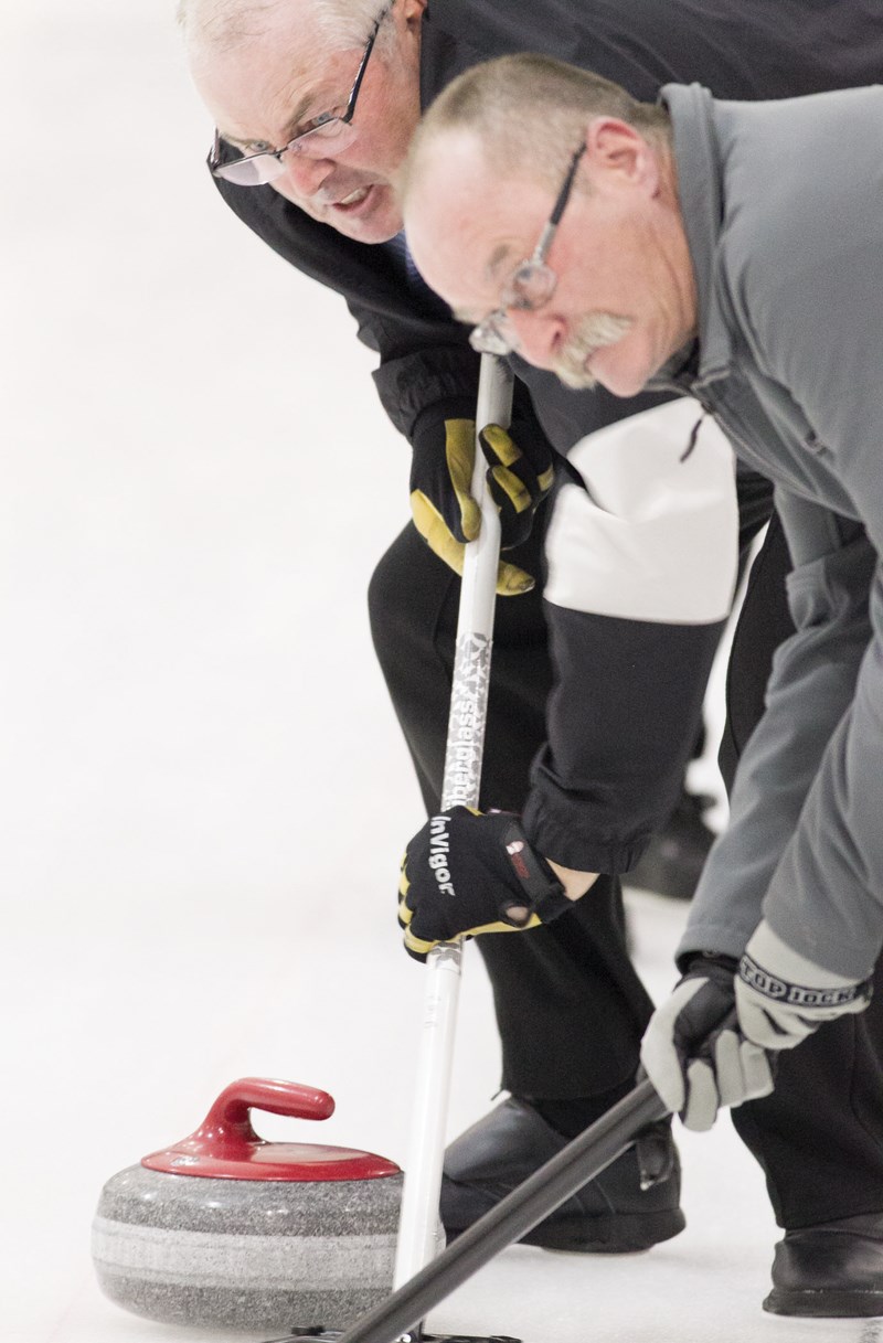 Rod Bradshaw, left, and Dave Goldstrom sweep a rock during the Olds Farmers and Farmerettes Bonspiel on Feb. 13. CLICK ON PHOTO FOR LARGER IMAGE