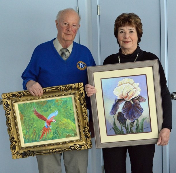 Dr. Dick Wray holds up his painting of a scarlet macaw. Next to him is Michele Brewster with her painting of a bearded iris. The pair will be featured at an exhibit held by