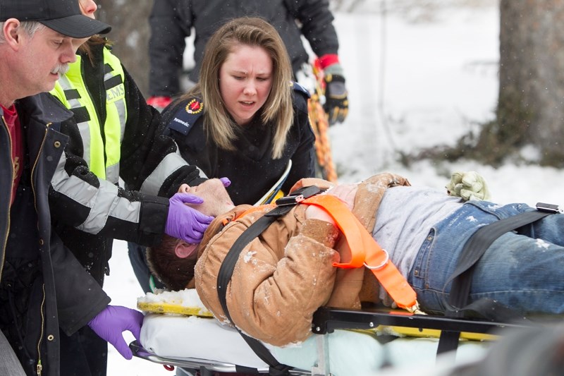 Paramedics rush an Olds College arboriculture student who fell 17 metres from a tree on campus on the afternoon of March 27 to a waiting ground ambulance. The student, Blaine 