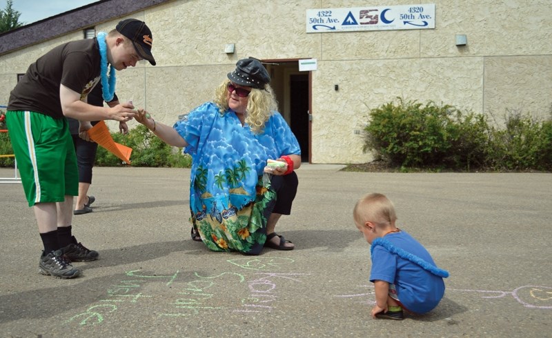 Mark Mengersen, left, takes a piece of chalk from Marj Cowan, centre, to write on the pavement. On the right is Mengersen&#8217;s nephew, Forrest Shandera. The three were at