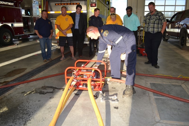 Members of the Rotary Club of Olds watch as Fire Training Officer Justin Andrews demonstrates how a new fire hose tester, purchased by the club, works. From left (behind