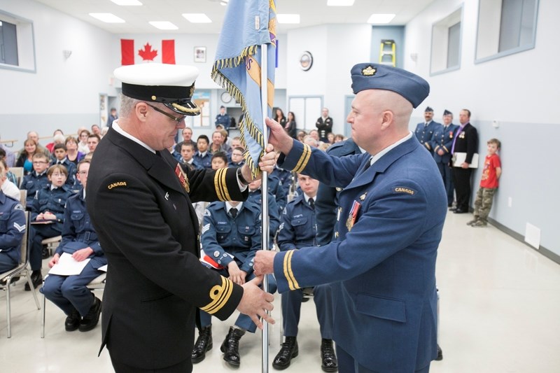 Lt.-Cmdr Bob Newton hands a flag to Capt. Ed Wiper signalling a change of command of the Olds Squadron No. 185 of the Royal Canadian Air Cadets at a ceremony at the Olds