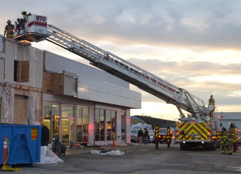 Firefighters check out the roof of Hildebrand Motors Wednesday after workers said they&#8217;d put out a small fire in the area.