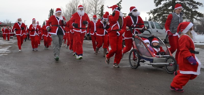 Participants in the first-ever Santa Run in Olds head out the Exhibition gates from the Cow Palace.