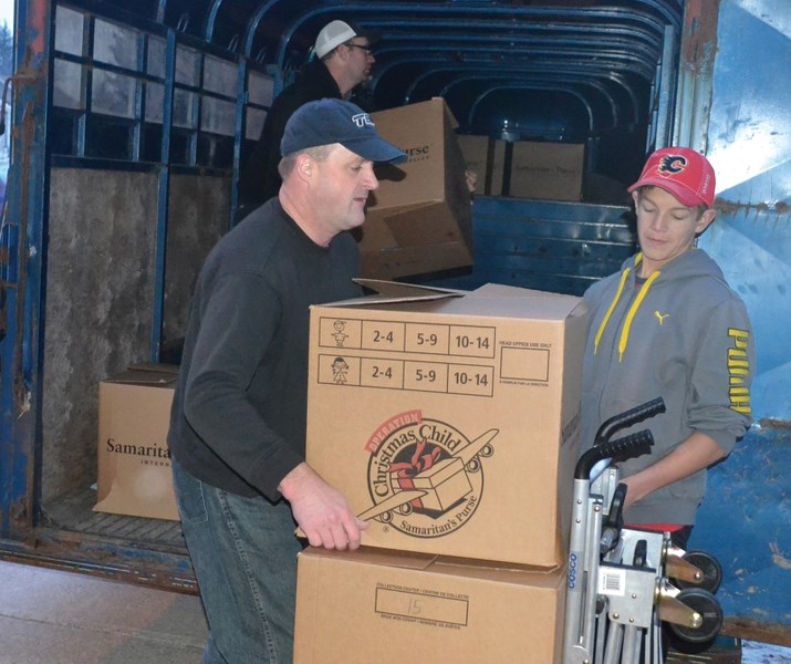 Glenn Mitchell and Brayden Pearson (right) help load Operation Christmas Child boxes into a horse trailer provided by Andy Boffey as Boffey puts them in place. Boffey donated 