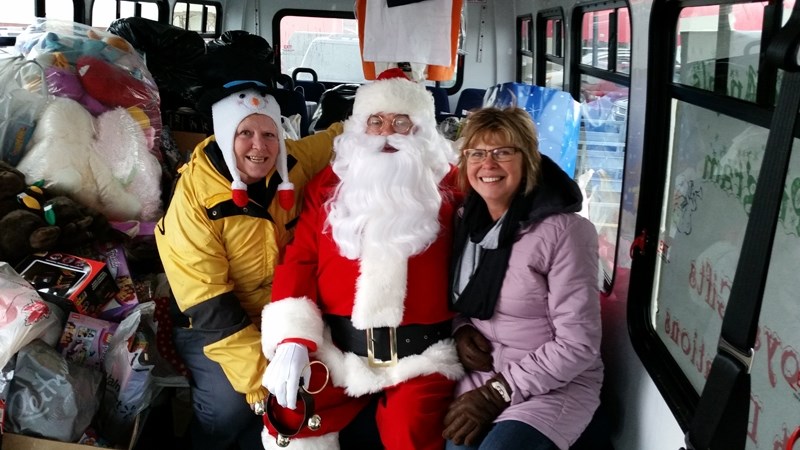 Santa Claus poses in the Sunshine Bus with Christmas Angels Heather De Boer and Debbie Chrusch.