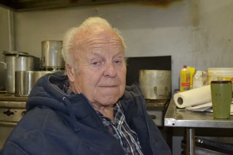 Christmas dinner organizer Henry Sollenberg sits just in front of his stove.