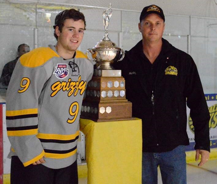 From left, Grizzlys forward Christopher Gerrie is presented with the trophy for the 2014 Canadian Junior Hockey League Rookie of the Year award from team president Shane