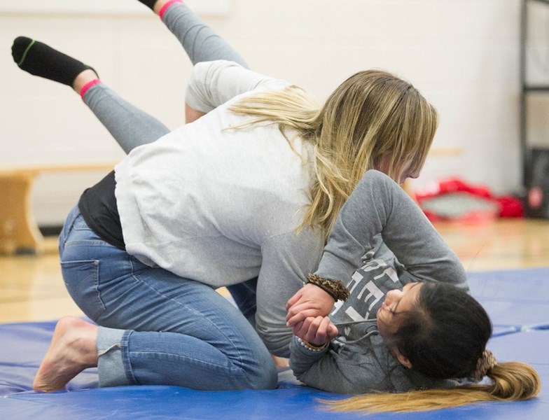 Danielle Lappage demonstrates a wrestling move on Grade 6 student Allona Dela Pena during her presentation at Holy Trinity School.