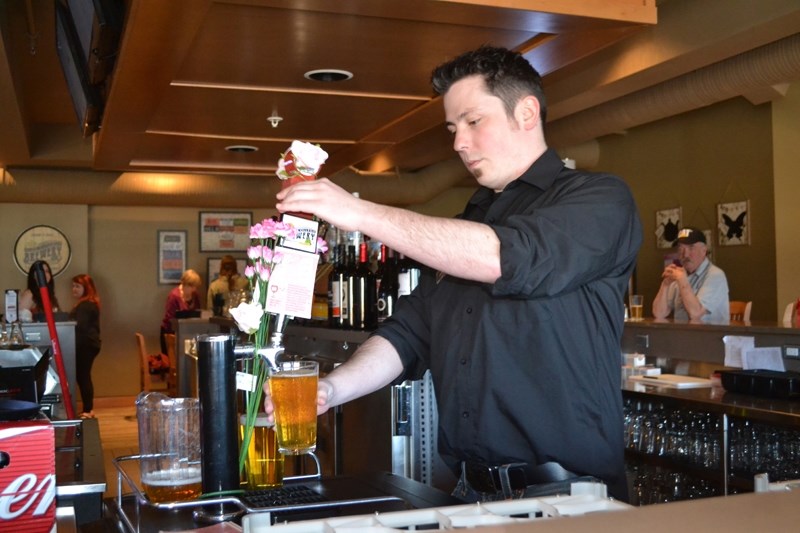 Bartender Hayden Strangway pours a glass of Little Sure Shot, a beer created by women in the Olds College brewmaster and brewery operations management program at Olds College.