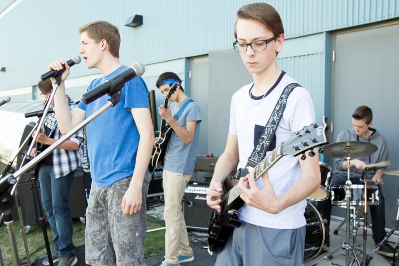 Russel Rabchak, left, and Riley Christopherson of the band Second Hand High perform before an Olds High School rugby game . In the background are bassist Brandon Carpenter,