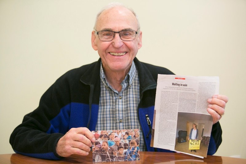 John Palardy holds up some of the information on Syrian refugees that he has gathered.