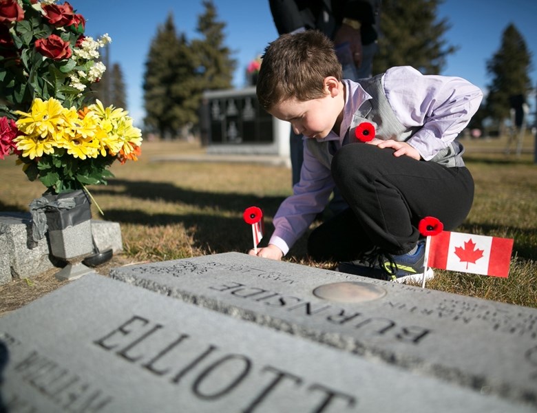 WE WILL REMEMBER THEM &#8211; Robert Anderson places a flag at a gravestone during the No Stone Left Alone ceremony at the cemetery Nov. 4.