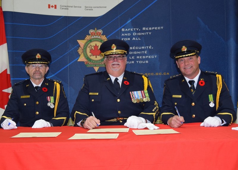 From left to right, outgoing Bowden Institution warden David Pelham, Correctional Service of Canada commissioner Don Head and incoming warden Tracey Farmer sign change of