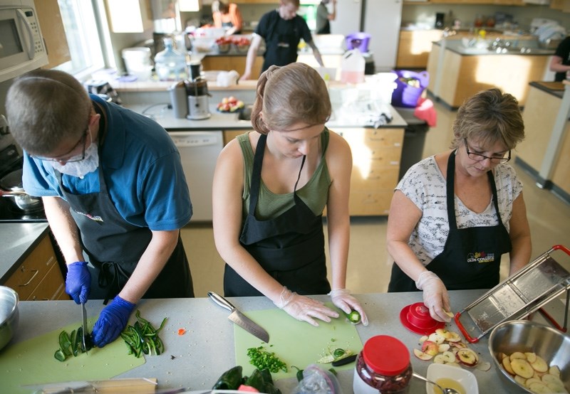 Ethan Nielson, left, and Jessa Muth, middle, prepare ingredients for salsa while Kim Goddard slices apples that will be made into apple chips.