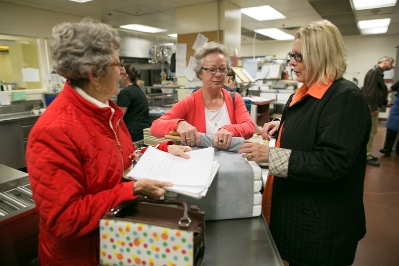 From left, volunteer coordinators Elsie Machell and Debby Fleming get Mayor Judy Dahl ready to help deliver a dinner as part of the meals on wheels program at Olds hospital.
