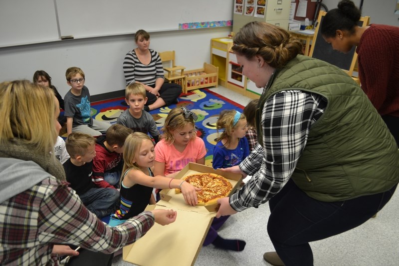 Abbey Iversen distributes pizza to kids in the Jungle Junction after-school program. Iversen is one of thousands of youth from across the country chosen to receive $150 under 