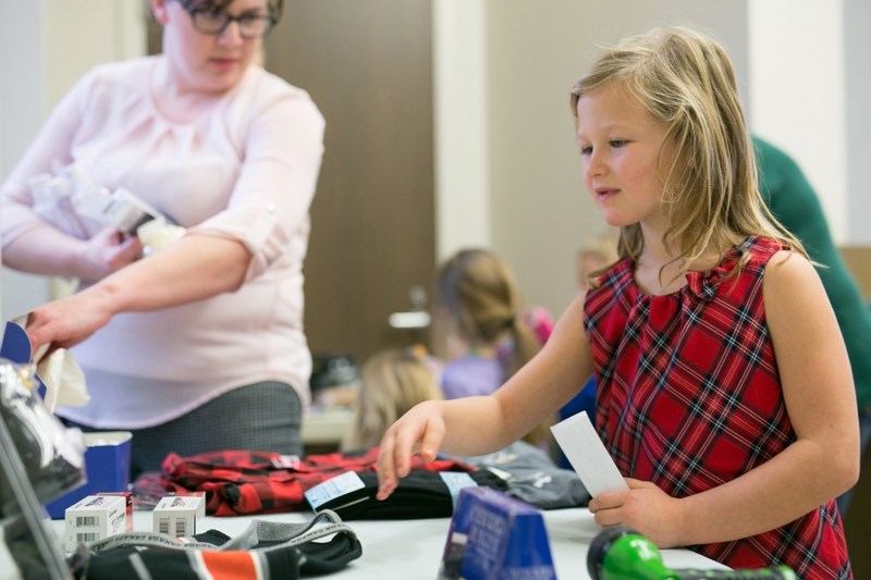 Briar Visser picks out Christmas presents during the first-ever Secret Santa fundraiser for the Christmas Angels at the Mountain View Credit Union.