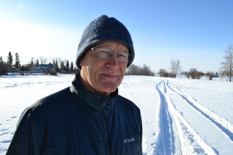Olds Nordic Skiers track-setter Warren Smith stands beside vehicle tracks that ran through an area where trails have been set up for cross-country skiers.