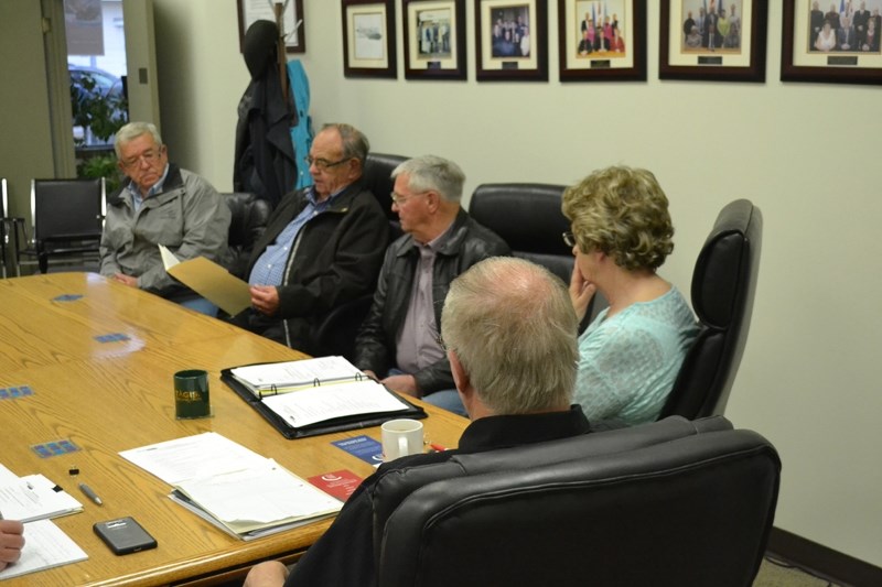 Don Peterson of the Friendship Centre Club consults his notes as he presents the club&#8217;s pitch to buy the land their building sits on from the town of Bowden. Looking on 