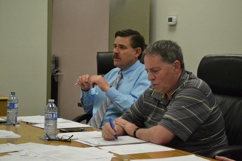 Bowden chief administrative officer James Mason monitors council deliberations as coun. Paul Webb checks out information on the council&#8217;s agenda package.
