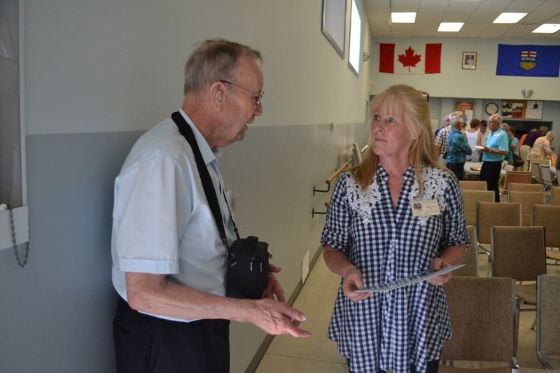 Former Olds resident Don Gibson, left, and Alvina Miller of the Sacramento, Calif. area discuss a photo Miller was given that shows former residents of the Wood&#8217;s Home.