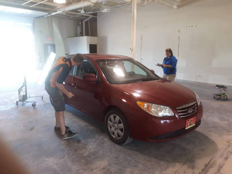 Employees of The Co-operators and Dent Force examine hail damage to a vehicle in Olds.