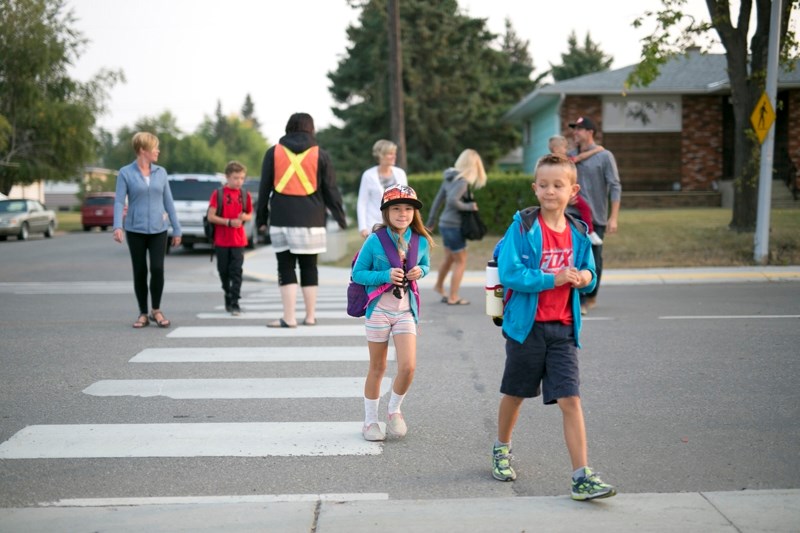 Students and parents/caregivers cross the street to get to Ècole Olds Elementary School.