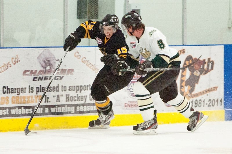 Olds Grizzlys player Spencer Dorowicz battles for possession of the puck against an Okotoks Oilers player during their game.