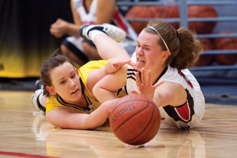 Olds College Broncos JV player Delaine Carl fights for possession of the ball against a CUC Aurora player during their game.