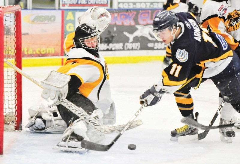 Grizzly netminder Brandon Thiessen stops a shot by Mustang Bryan Arneson as the Olds grizzlys host the Calgary Mustangs in AJHL playoff hockey action last Tuesday night.
