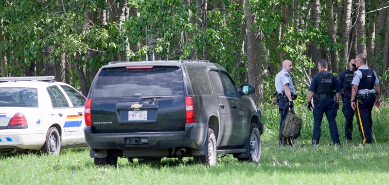 RCMP officers gather at a location where a man and a woman were arrested west of Bowden on June 12.