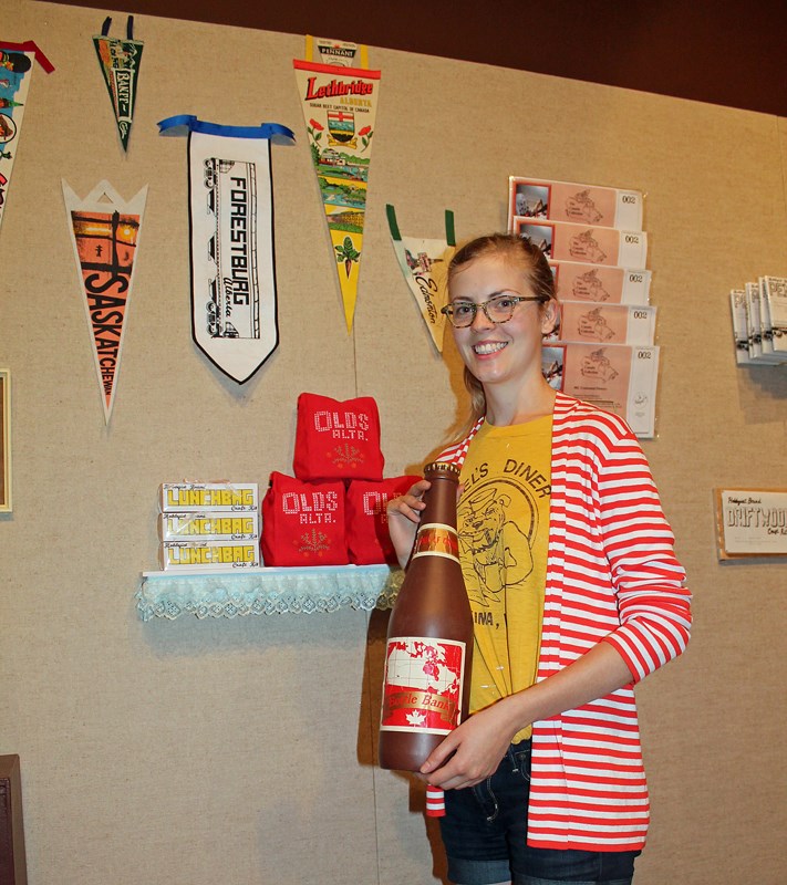 Arianna Richardson of Lethbridge stands with some of the souvenirs, crafts and hobby kits that make up her travelling art exhibition called Canada Collection in Olds, which