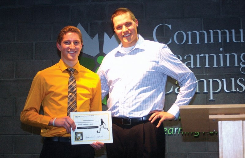 Connor Jorgensen accepts the award for the top rookie on the Olds High School Spartans football team from Blake Machan, an assistant coach with the team. The award was