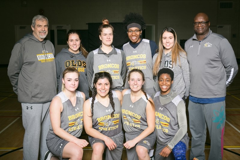 The Olds College Broncos basketball team with head coach Avery Harrison, left, and associate coach Peter Sambu, right, at the Ralph Klein Centre.