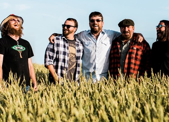 Members of the Blake Reid Band share a laugh in a field where a recording project and documentary on the recording were created.
