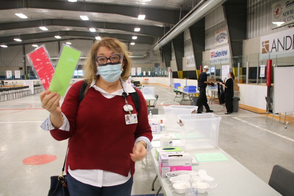 Gayle Seddon, Southlake Regional Health Centre director of community programs, holds up the red and green cards vaccinators will use to signal people.