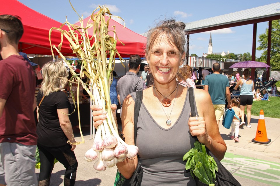The Newmarket Farmers' Market has been going strong throughout the month. Heidi Vanhoogmoed (pronounced "Smith") with a bunch of garlic bulbs at the July 22 Newmarket Farmers' Market.  Greg King for NewmarketToday.