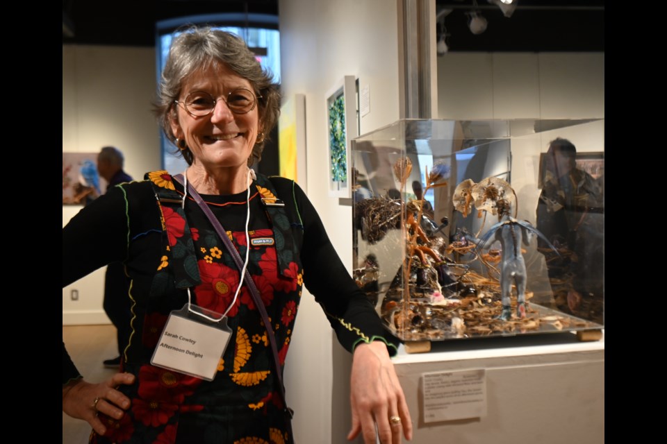 Sarah Crowley of Beaverton stands next to her piece, Afternoon Delight, at the reception at the Old Town Hall for the Newmarket Juried Art Show April 18. "I like to create an environment and whimsical and intriguing stories, where the viewer can see the piece and then they end up being pulled into it." 