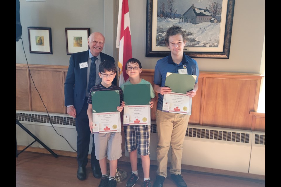 Tony Van Bynen (left) presents the certificates and pins to Jake, Owen, and Nathan Tubaro. 