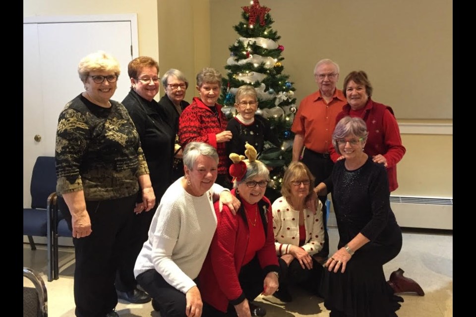 Kitchen staff and lunch organizers gathered around the Christmas tree at the Aurora Bridge Club's annual holiday lunch and bridge event Dec. 2.