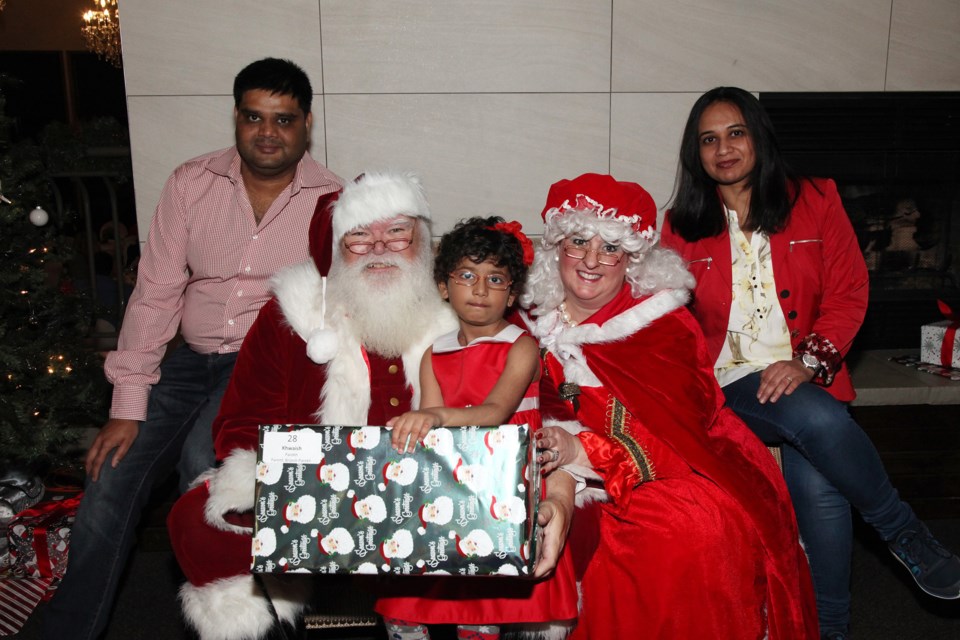 Khwaish gets a present from Santa, here with parents Brijesh and Shweta Parekh, at the Pediatric Christmas Party at Cardinal Golf Club last night.  Greg King for Newmarket Today